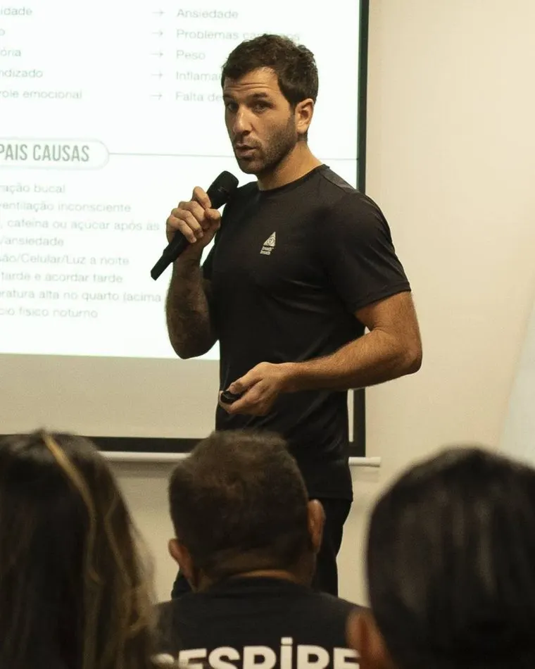 Samir Murad falando ao microfone para uma turma, com slides sobre sono e ansiedade ao fundo